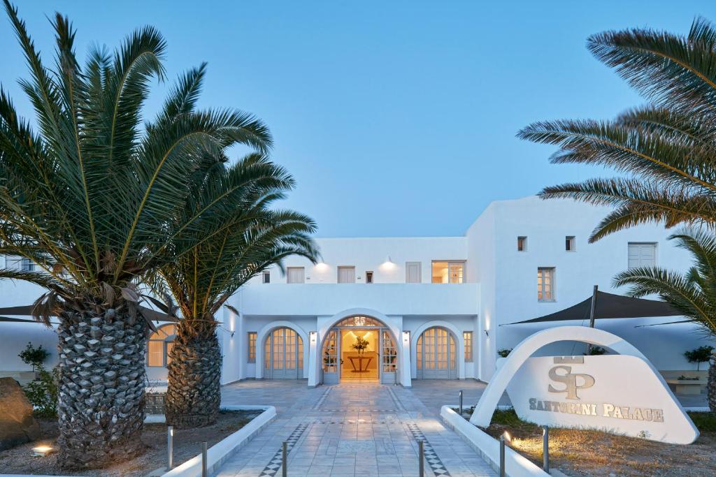 a view of the front of a hotel with palm trees at Santorini Palace in Fira