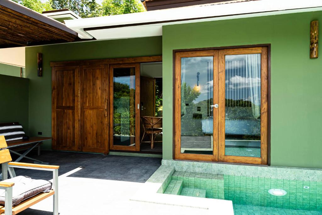 a green house with a swimming pool and sliding glass doors at Mae Ya Resort in Ko Tao