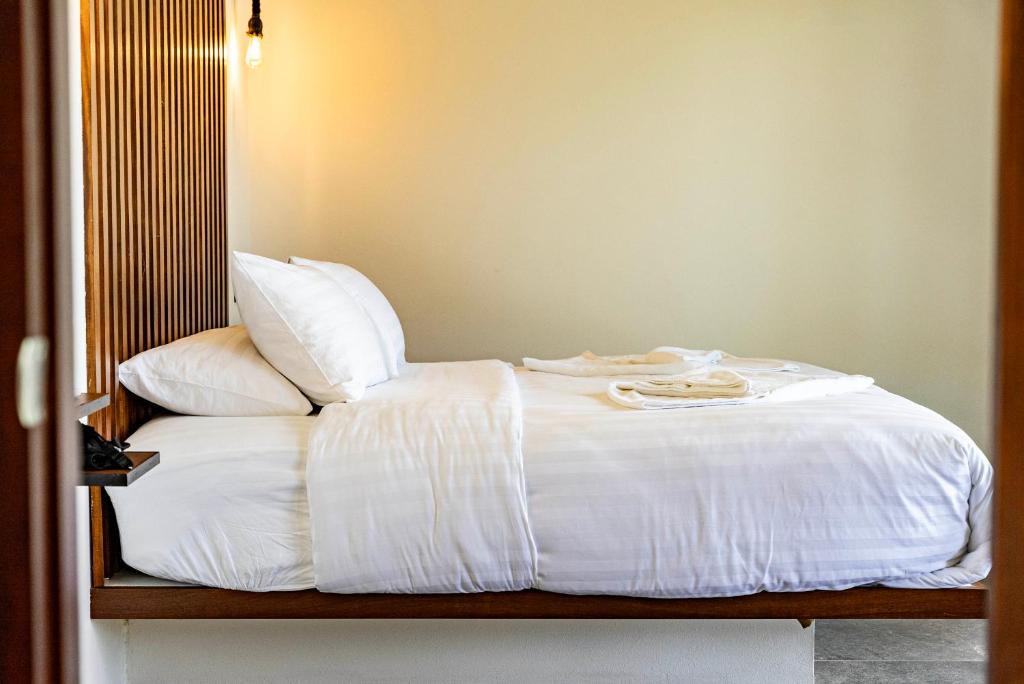 a bed with white sheets and pillows on it at Mae Ya Resort in Ko Tao