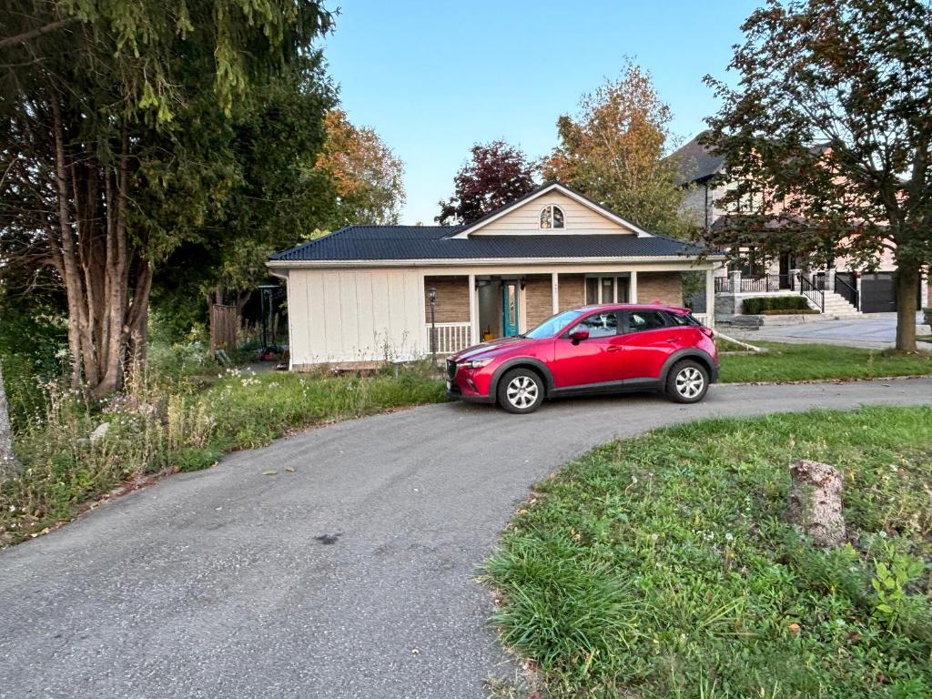 a red car parked in front of a house at Entire bungalow, full privacy, free parking in Oshawa
