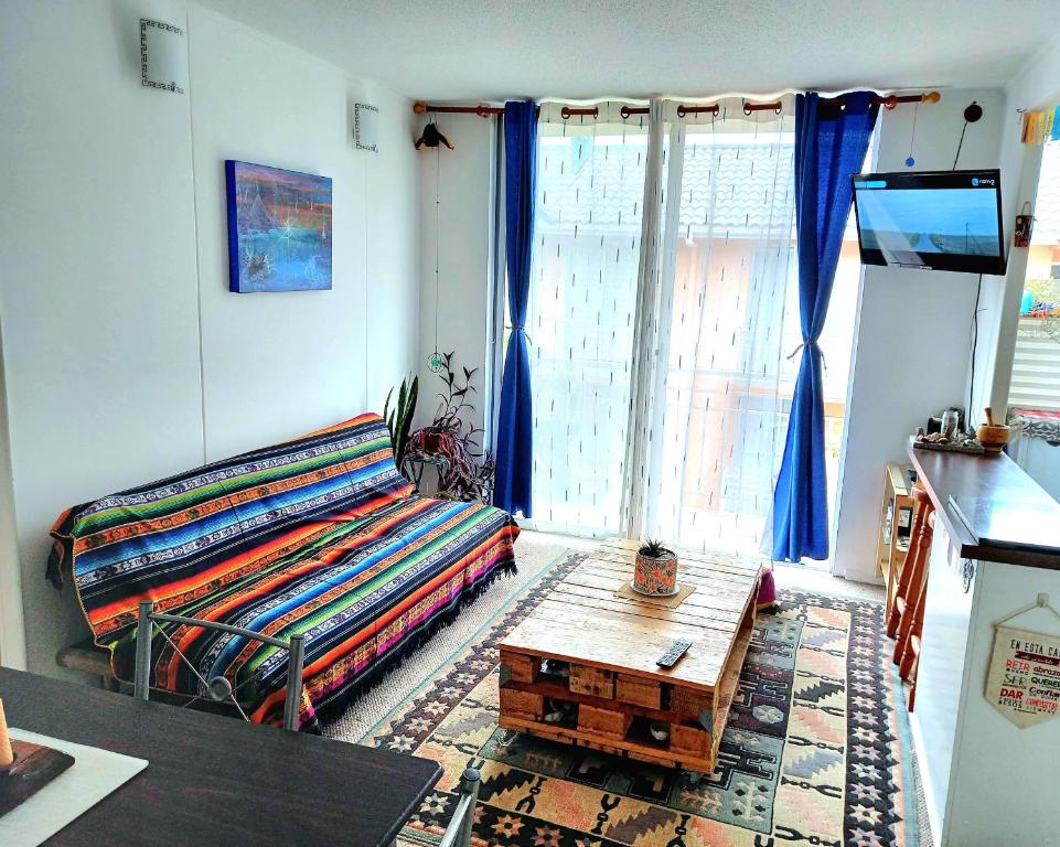 a living room with a bed and a coffee table at Acogedor departamento veraneo a pasos de la avenida del Mar in La Serena