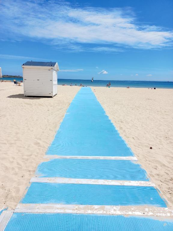 - un tapis bleu sur la plage à côté d'une cabane dans l'établissement Studio du départ pour les îles Quiberon, à Quiberon