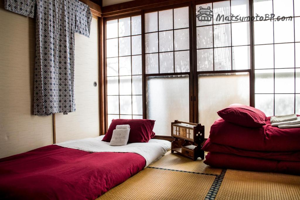 um quarto com uma cama e uma cadeira em frente a uma janela em Matsumoto BackPackers em Matsumoto