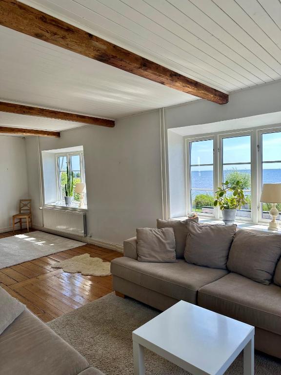 a living room with a couch and some windows at Strandnära hus Abbekås in Abbekås