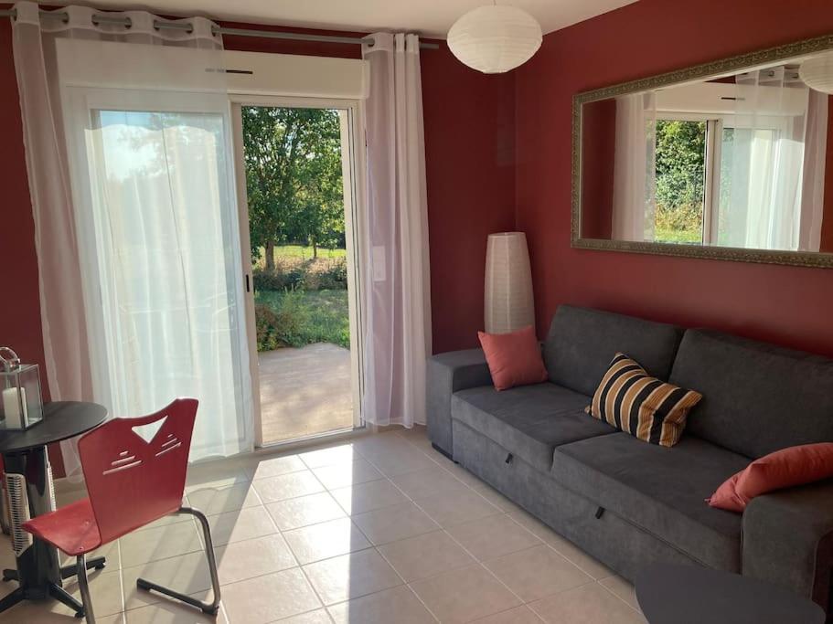 a living room with a gray couch and a window at l'atelier in Saint-Lubin-en-Vergonnois