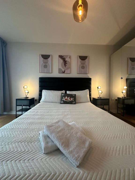 a bedroom with a large white bed with two lamps at Lovely flat in Kingston Town in Kingston upon Thames