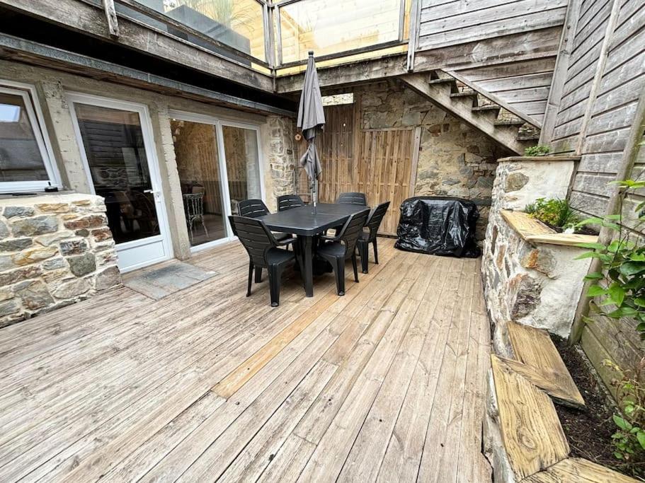 une terrasse en bois avec une table et des chaises. dans l'établissement Appartement rue des artistes, à Camaret-sur-Mer