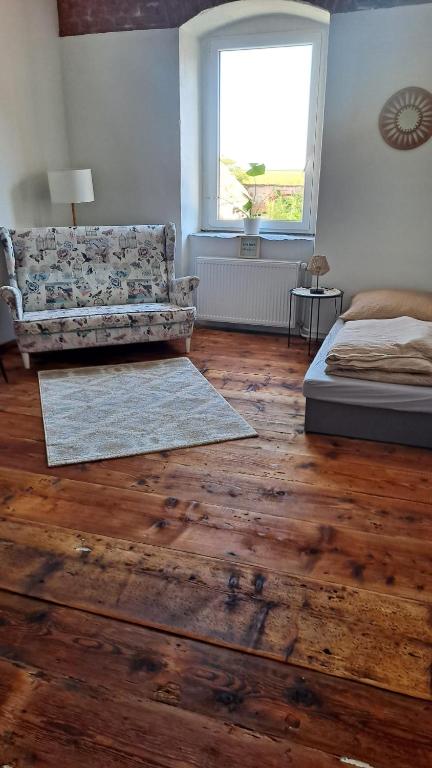 a bedroom with a couch and wooden floors and a window at Noclegi Czentorycki 3 in Tyniec nad Ślęzą