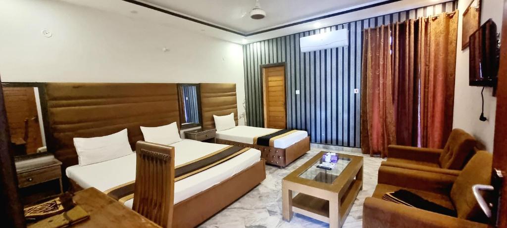 a room with a bed and a couch and a table at Pakeeza One Hotel in Lahore