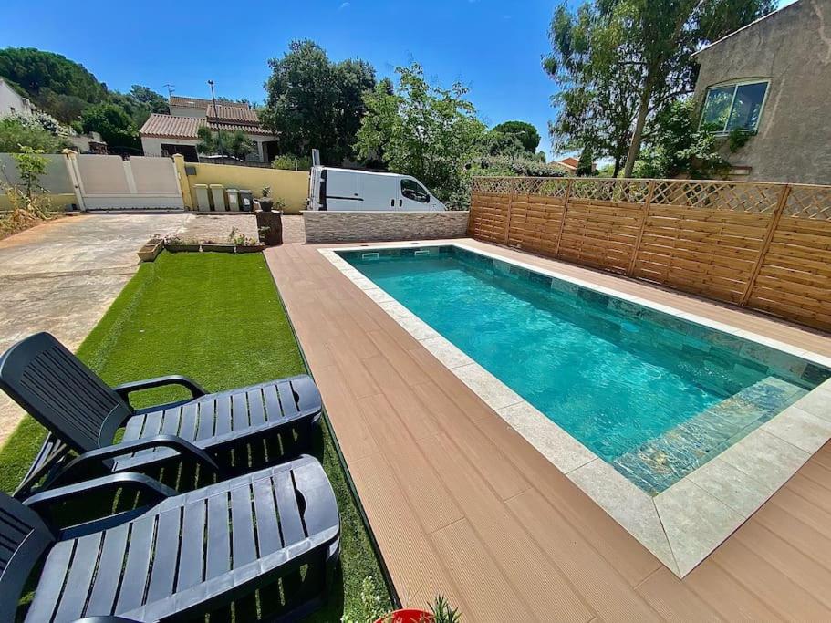 - une piscine dans une cour avec 2 chaises longues dans l'établissement 4 pieces avec piscine, à Baillargues