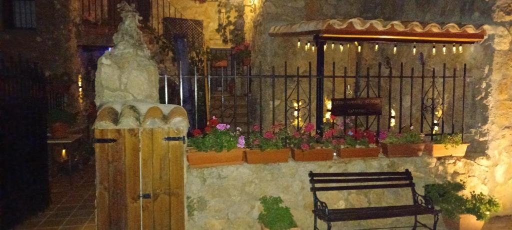 a bench in a building with flowers and a fence at Casas Rurales el Olmo in Riópar Viejo
