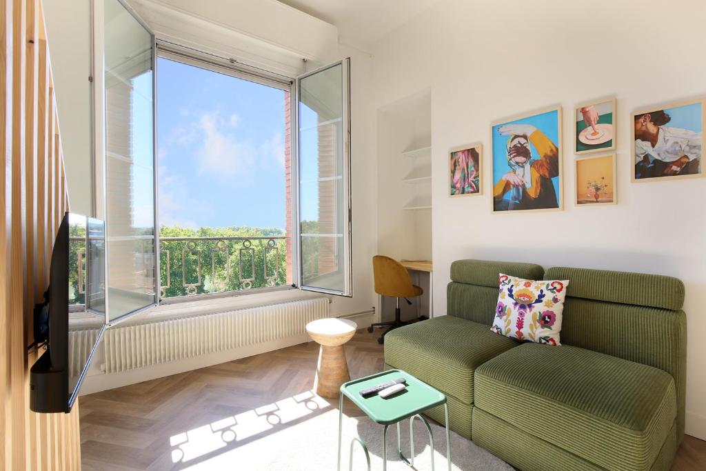 un salon avec un canapé et une grande fenêtre dans l'établissement Vue imprenable et charme historique à Toulouse, à Toulouse