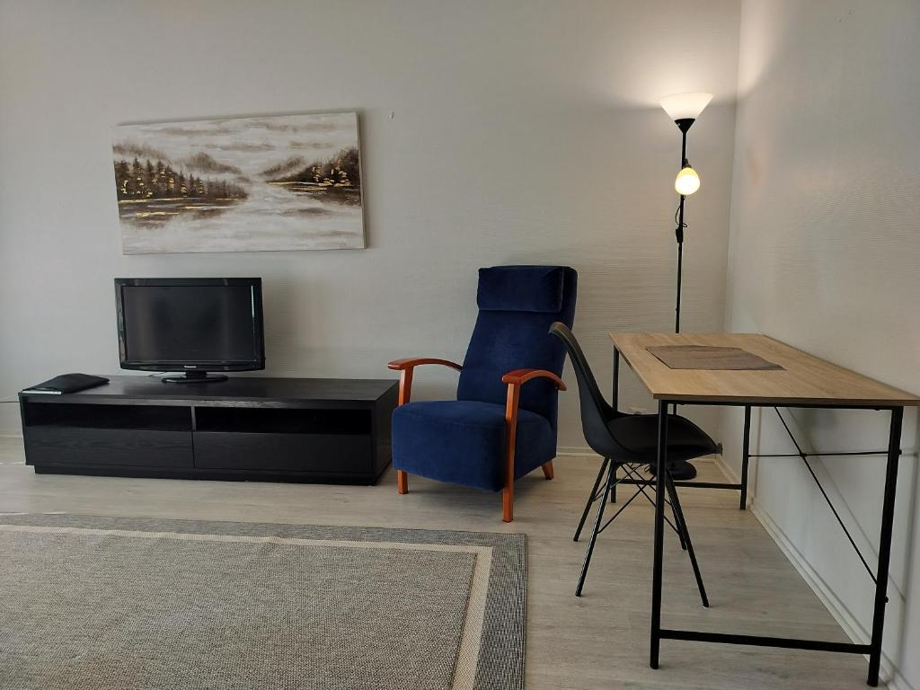 a living room with a table and a chair and a television at Kolmio Kokkola in Kokkola