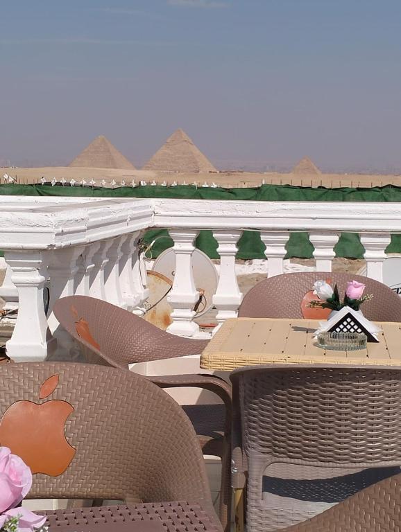 un patio al aire libre con mesas y sillas en el balcón en Pyramids High View Inn, en Giza
