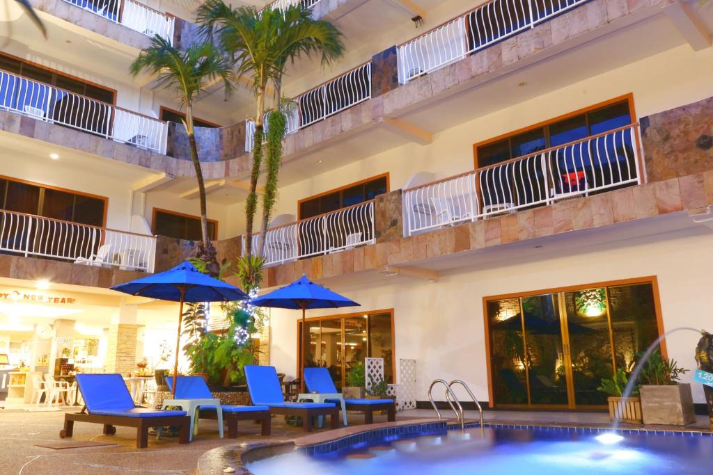 a hotel with a pool and chairs and umbrellas at Baan Boa Resort in Patong Beach