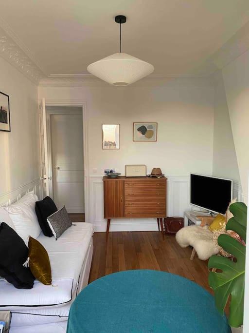 un salon avec un canapé blanc et une télévision dans l'établissement Charmant Appartement Typique Parisien, à Paris