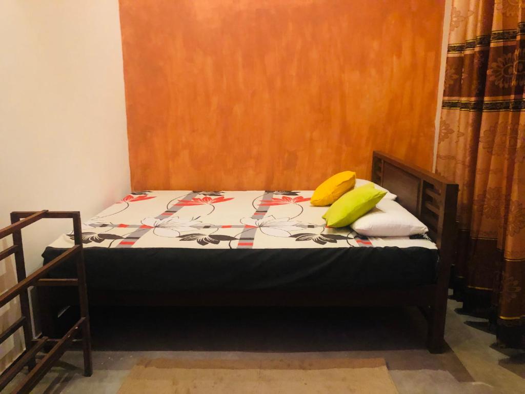 Una cama pequeña con dos almohadas amarillas. en Suriya Accommdation, en Matara