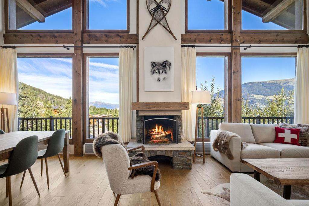 a living room with a fireplace with a view of mountains at 200m ski slopes - Chalet Manora - Courchevel La Tania in Courchevel