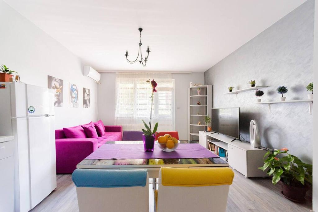 a kitchen and living room with a table and a pink couch at Апартамент Веирас 2 in Velingrad