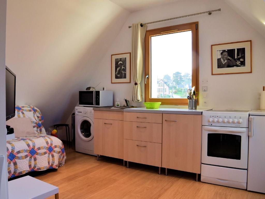 a kitchen with a stove and a microwave and a window at A deux pas des îles in Penvénan