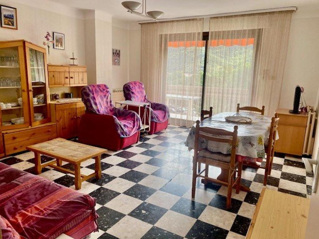 a living room with a couch and a table and chairs at Charmant F2 avec Garage, Terrasse et Véranda, à 500m du Centre et 600m des Cures à Amélie-les-Bains - FR-1-703-131 in Amélie-les-Bains-Palalda