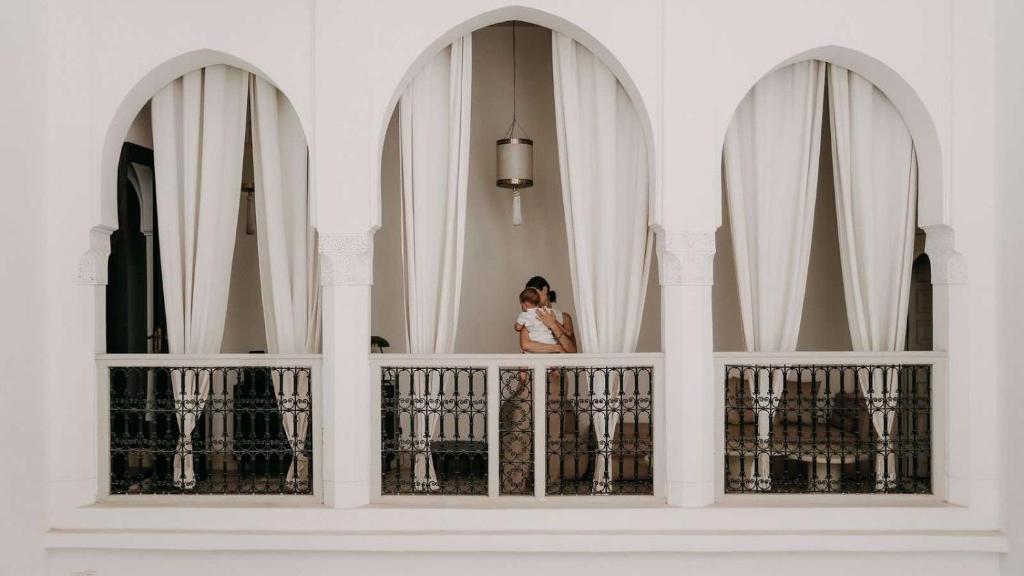 une femme debout sur le balcon d'un bâtiment dans l'établissement Riad KRÈME, à Marrakech