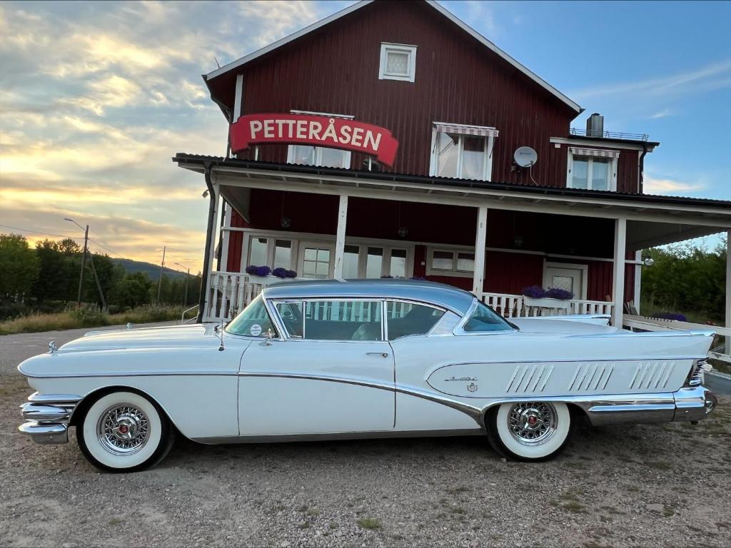 a white car parked in front of a red building at Petteråsens Guest room in Torsby