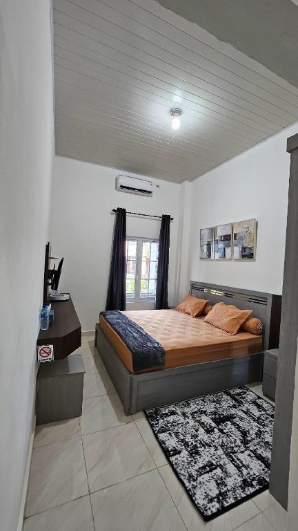 a bedroom with a bed and a desk in it at Ghania homestay syariah meulaboh in Meulaboh