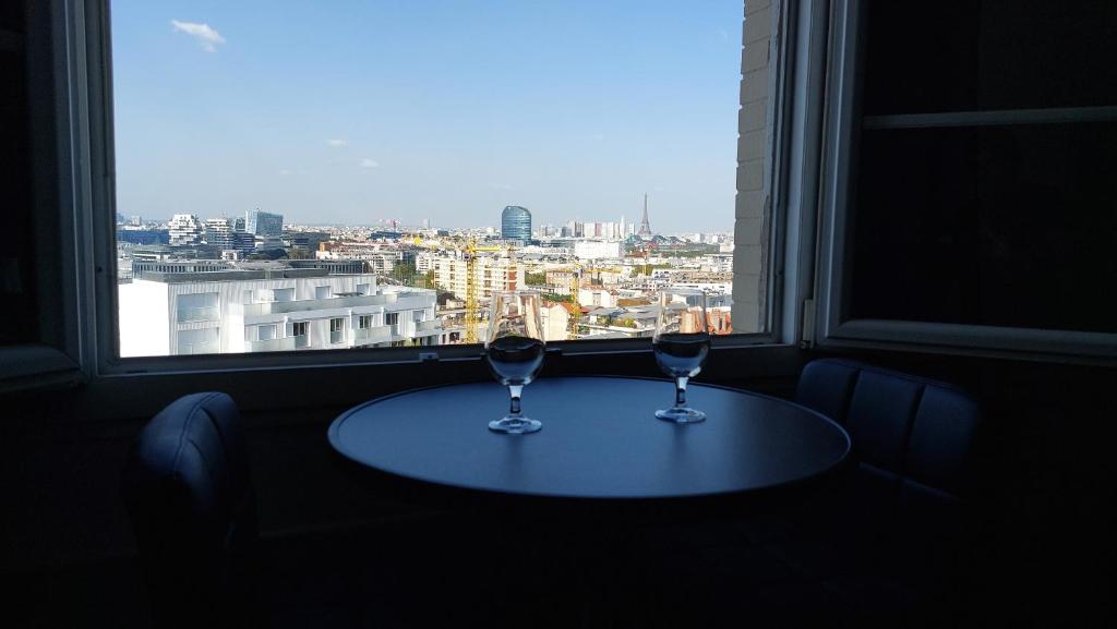 deux verres à vin assis sur une table devant une fenêtre dans l'établissement Apartment with a superb view on Eiffel Tower, à Issy-les-Moulineaux