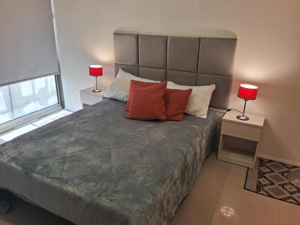 a bedroom with a large bed with two red lamps at Torre Esmeralda 740 in Buenos Aires