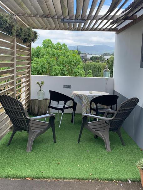 a patio with three chairs and a table on the grass at SERMAR 1 in Rabo de Peixe