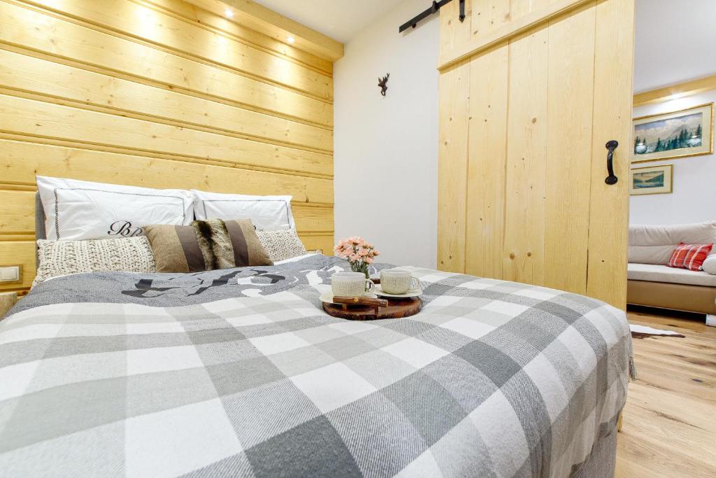 1 dormitorio con 1 cama grande y pared de madera en Apartament Chałubińskiego, en Zakopane