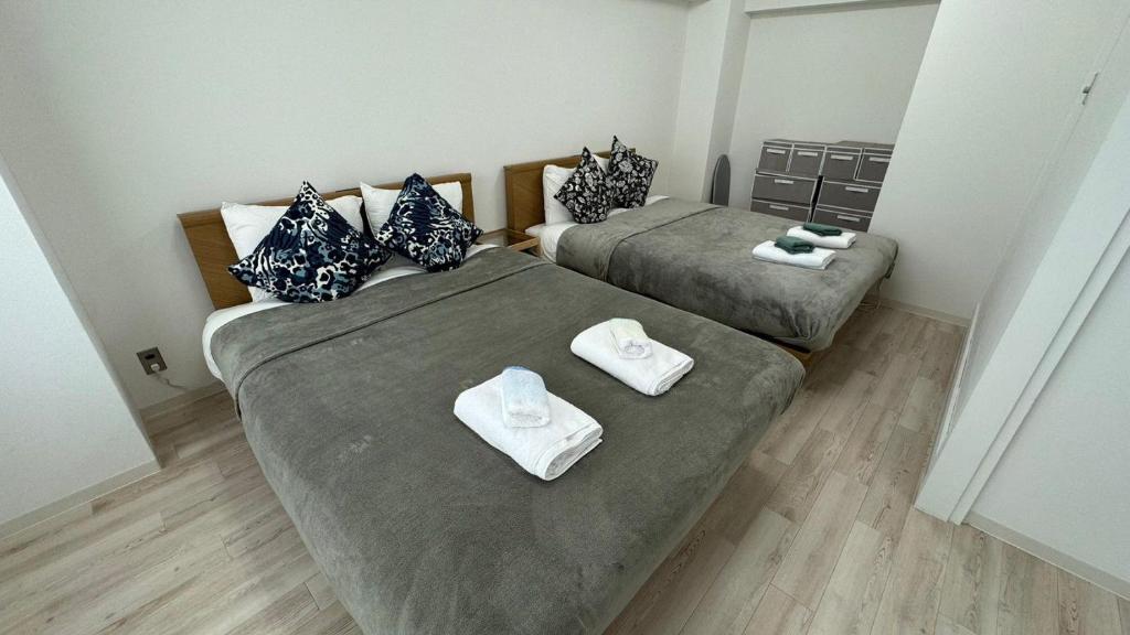 two beds in a small room with towels on them at JR Shin-Osaka 30s, Direct to Kansai Airport 關西空港直達,Shinkansen to Tokyo, Tokyo & Nagoya, Universal Studio 16 mins, Umeda 6 mins, Kyoto 25 mins, Early Check-In in Osaka