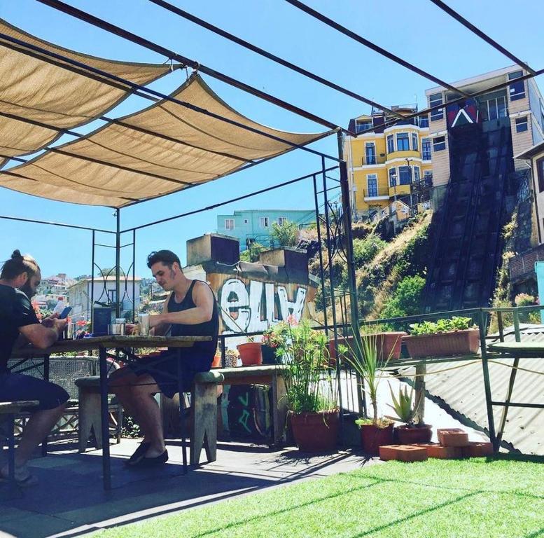 zwei Männer sitzen an einem Tisch unter einem Sonnenschirm in der Unterkunft Casa Elias Hostel in Valparaíso