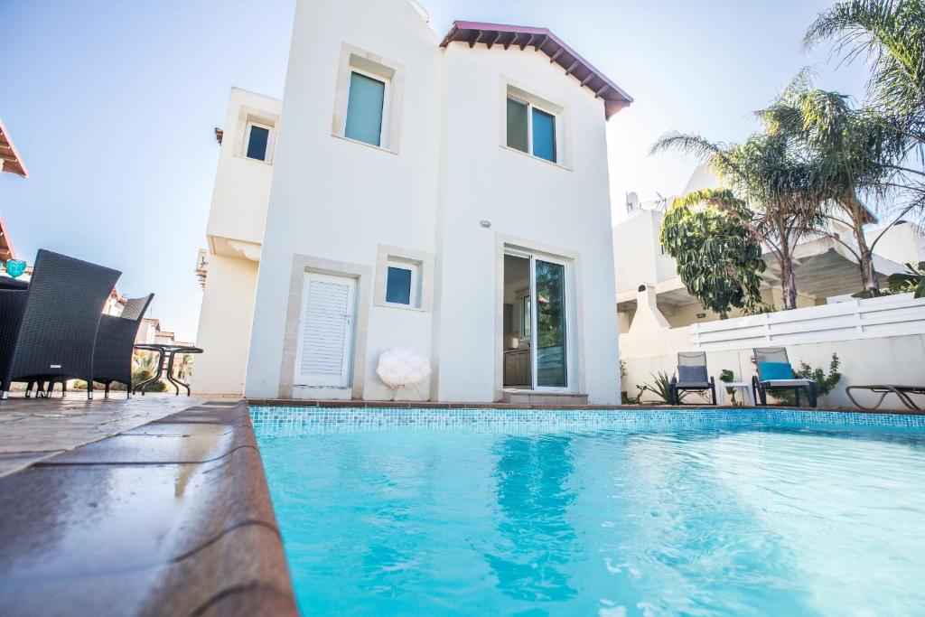 a villa with a swimming pool in front of a house at Seaspray in Protaras