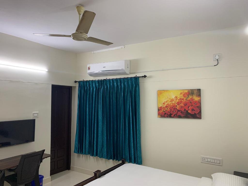 a room with a ceiling fan and a painting on the wall at Archrose Villa in Trivandrum