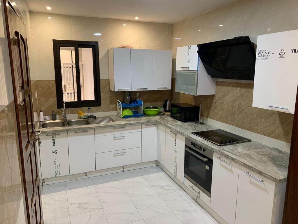 a kitchen with white cabinets and a sink and a stove at Mubi House in Kinshasa