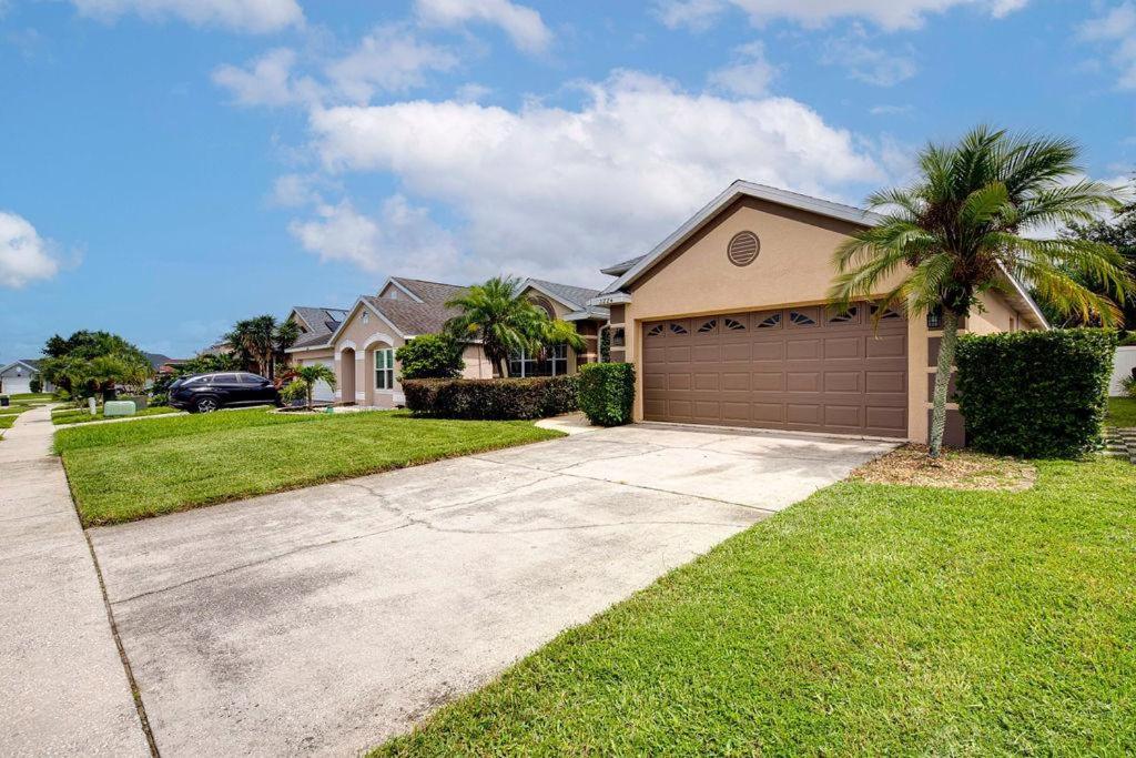 a house with a garage and a palm tree at Stunning 3 Bed Former Model Home in Orlando
