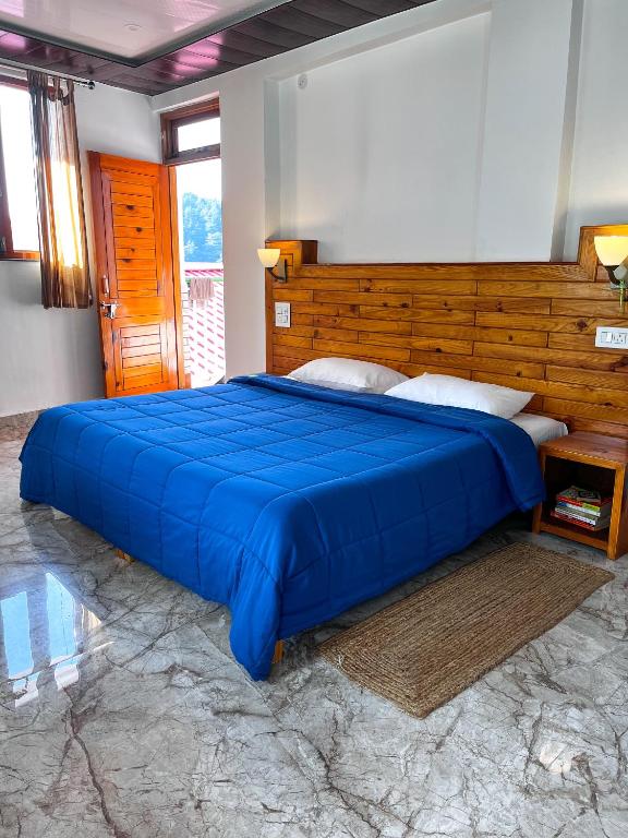 a bedroom with a blue bed with a wooden headboard at Yutori Stays in Dharamshala