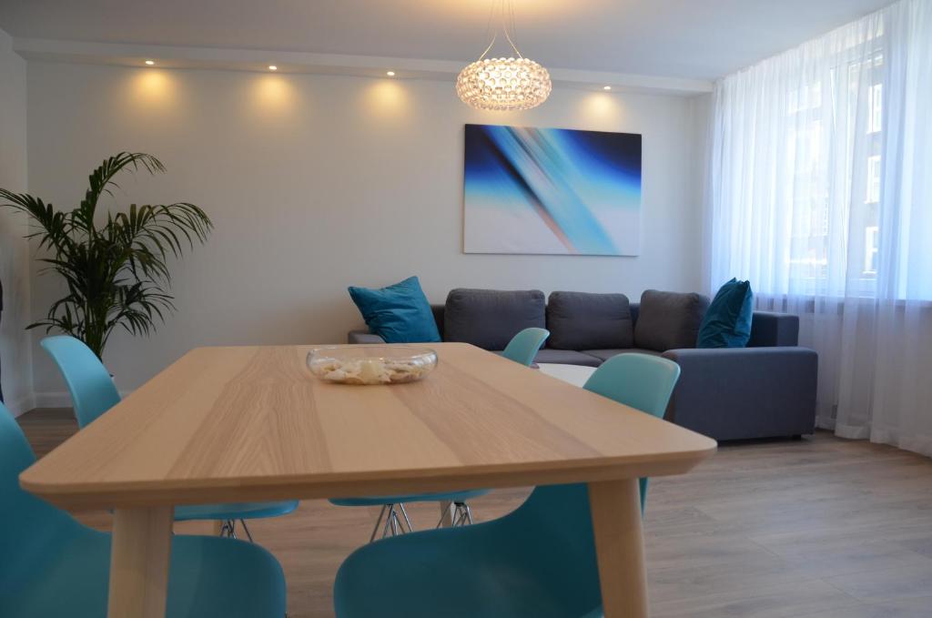 a dining room with a wooden table and blue chairs at Apartament na Starówce Grobla I in Gdańsk