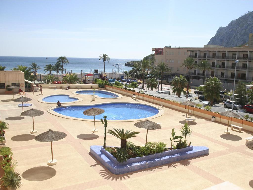 un grupo de tres piscinas con sombrillas y el océano en Apartamentos Zafiro Unitursa, en Calpe