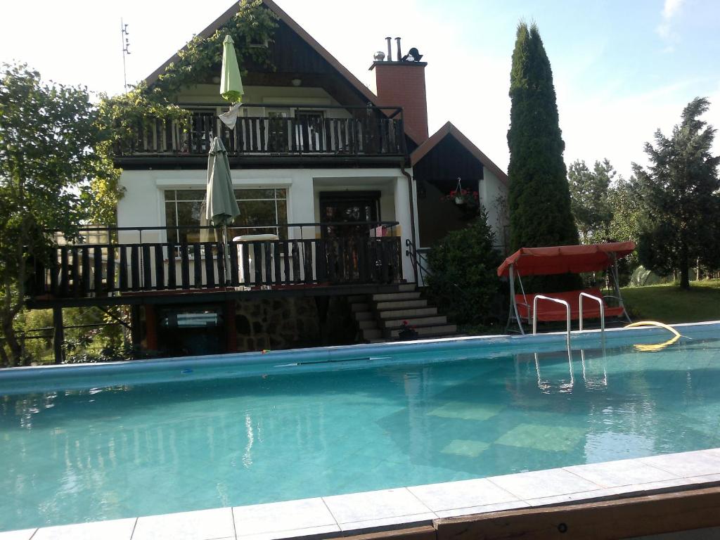 a house with a swimming pool in front of a house at Holiday Villa Żuromino in Żuromino