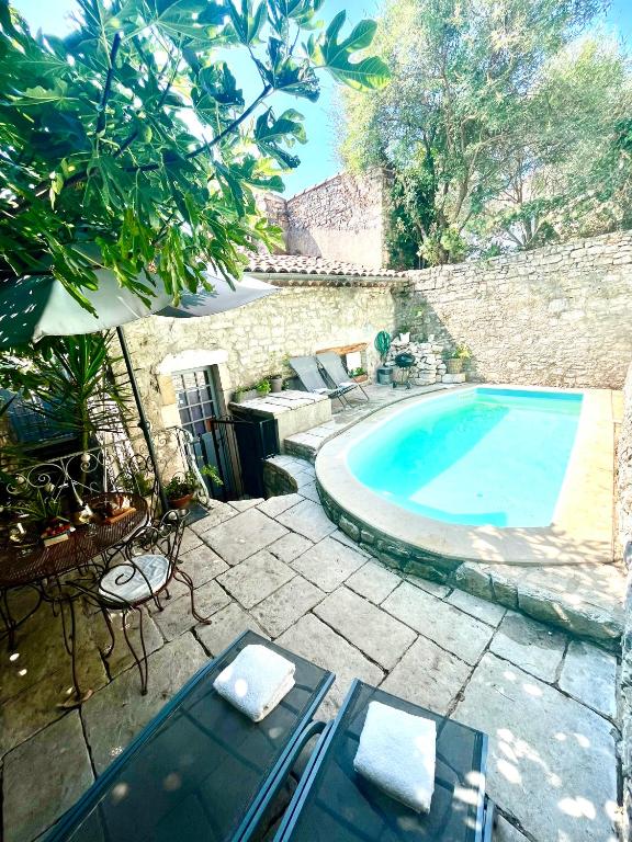 - une piscine dans une cour dotée d'un mur en pierre dans l'établissement Maison du Vigneron, à Vézénobres