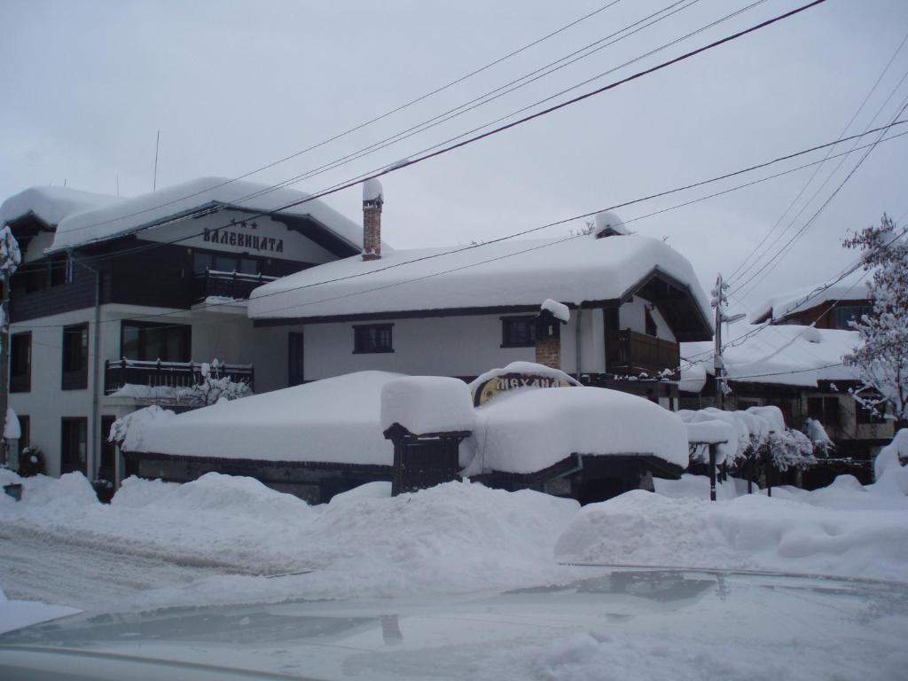 een groep met sneeuw bedekte auto's geparkeerd voor een gebouw bij Guest House Valevicata in Bansko