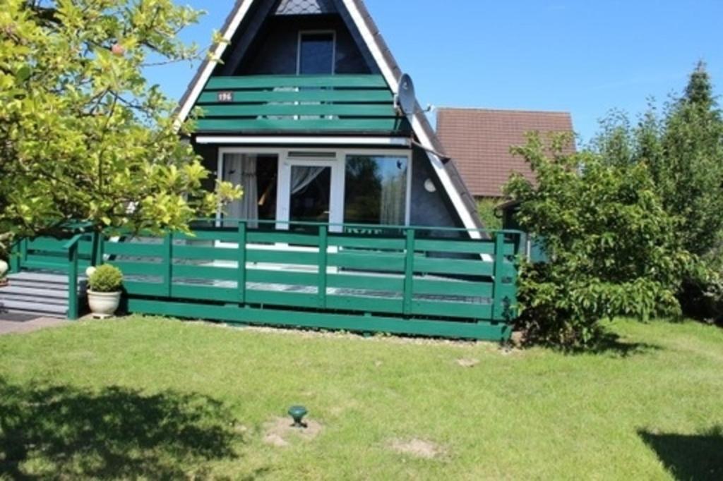 ein grünes Haus mit einem grünen Zaun im Hof in der Unterkunft Ferienhaus 196 in Fedderwardersiel in Fedderwardersiel