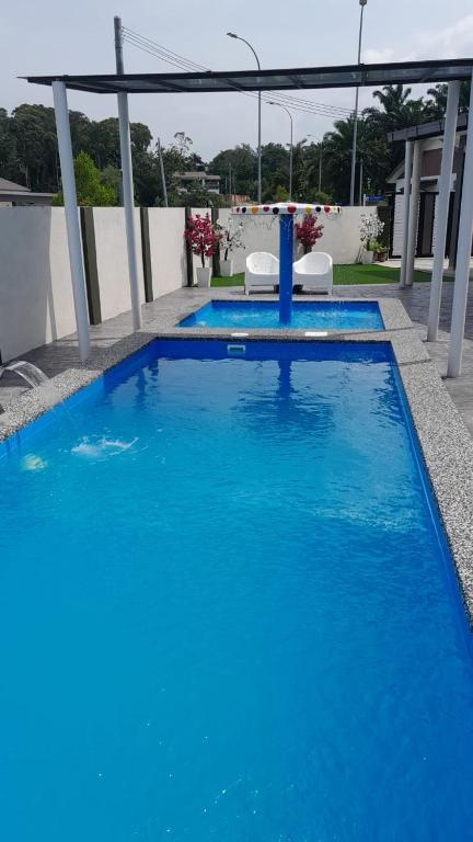 a large blue swimming pool with two chairs on a building at LaRinDa Teluk Kemang Private Pool - Islamic in Port Dickson