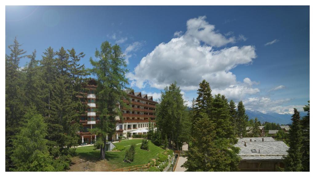 a building in the middle of a forest of trees at Hotel Royal in Crans-Montana
