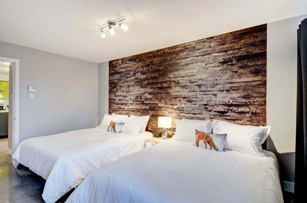 2 Betten in einem Zimmer mit Ziegelwand in der Unterkunft L'Express in Saint-Férréol-les-Neiges