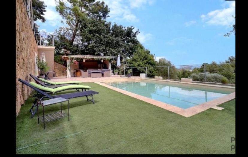 une piscine avec une pelouse verdoyante et une maison dans l'établissement Charmante bastide, au Cannet-des-Maures