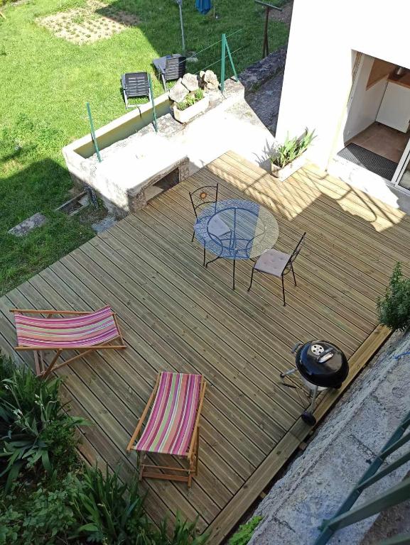 une terrasse en bois avec une table, des chaises et un grill dans l'établissement Logement avec terrasse Millau, à Millau